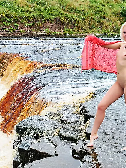 Pale babe with small boobies bending and teasing at the waterfal