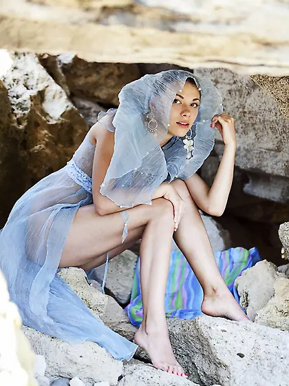 Karin P is sitting on rocks in transparent cape and naughtily sp