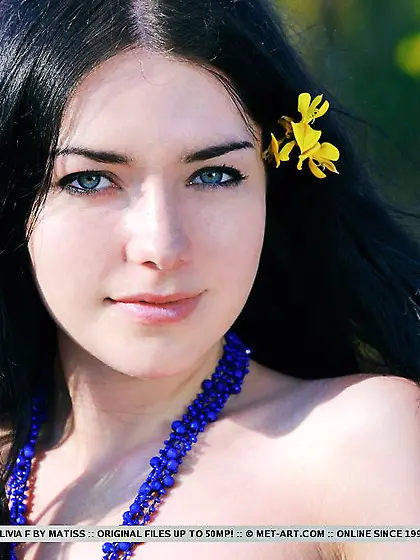 There is a flower in Olivia F's dark hair and she looks more tha