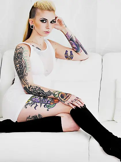 Female covered with tattoos puts black leg warmers on to undersc