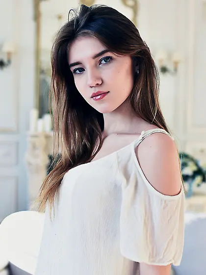 White get-up beauty slowly undressing to pose naked on a couch V